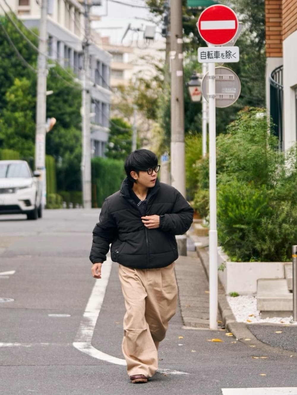 ブラック系のダウンジャケット/コート、ホワイト系のチノパンツ、ブラウン系のモカシン/デッキシューズを着用したメンズの秋コーディネートの3枚目の写真