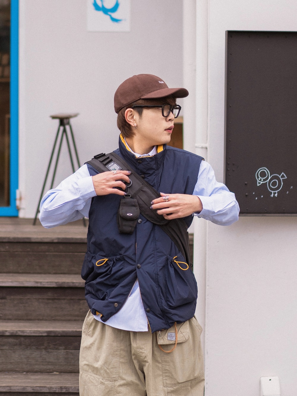 ブルー系のダウンベスト、グレー系のスニーカー、ブラウン系のキャップを着用したメンズの冬コーディネートの2枚目の写真