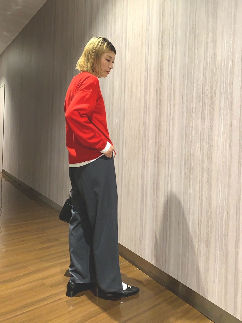 レッド系のニット/セーター、グレー系のその他パンツ、ブラック系のショルダーバッグを着用したレディースの秋コーディネートの2枚目の写真