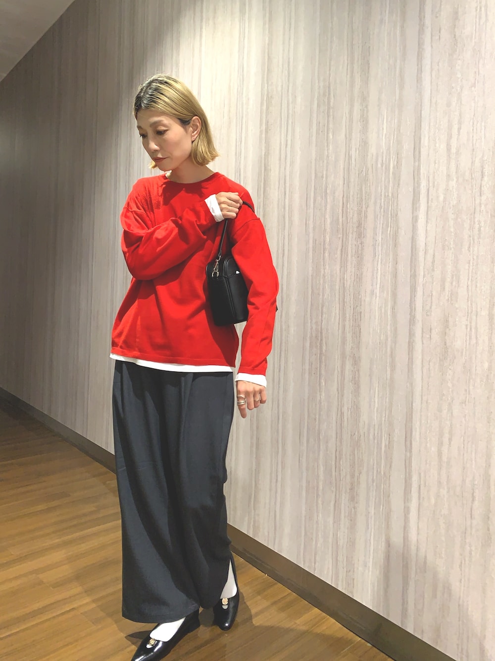 レッド系のニット/セーター、グレー系のその他パンツ、ブラック系のショルダーバッグを着用したレディースの秋コーディネートの5枚目の写真