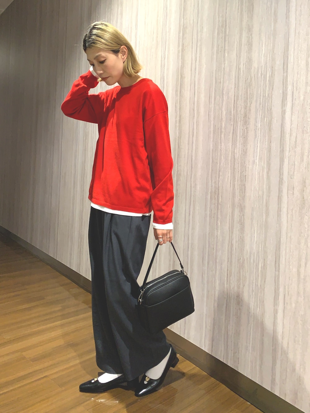 レッド系のニット/セーター、グレー系のその他パンツ、ブラック系のショルダーバッグを着用したレディースの秋コーディネートの4枚目の写真