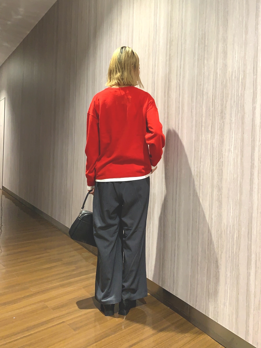 レッド系のニット/セーター、グレー系のその他パンツ、ブラック系のショルダーバッグを着用したレディースの秋コーディネートの3枚目の写真