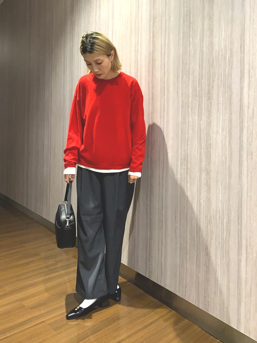 レッド系のニット/セーター、グレー系のその他パンツ、ブラック系のショルダーバッグを着用したレディースの秋コーディネートの6枚目の写真