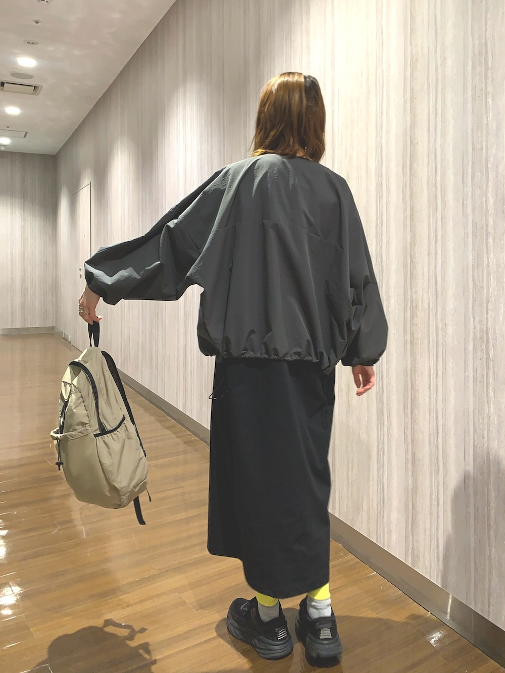 ブラック系のワンピース、グレー系のカーディガン/ボレロ、ベージュ系のバックパック/リュックを着用したレディースの春コーディネートの7枚目の写真