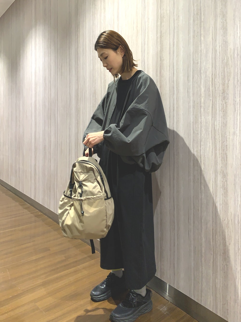 ブラック系のワンピース、グレー系のカーディガン/ボレロ、ベージュ系のバックパック/リュックを着用したレディースの春コーディネートの2枚目の写真