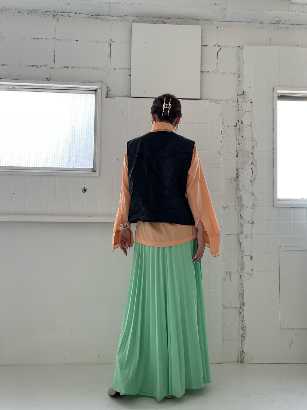 オレンジ系のトップスを着用したレディースの夏コーディネートの2枚目の写真