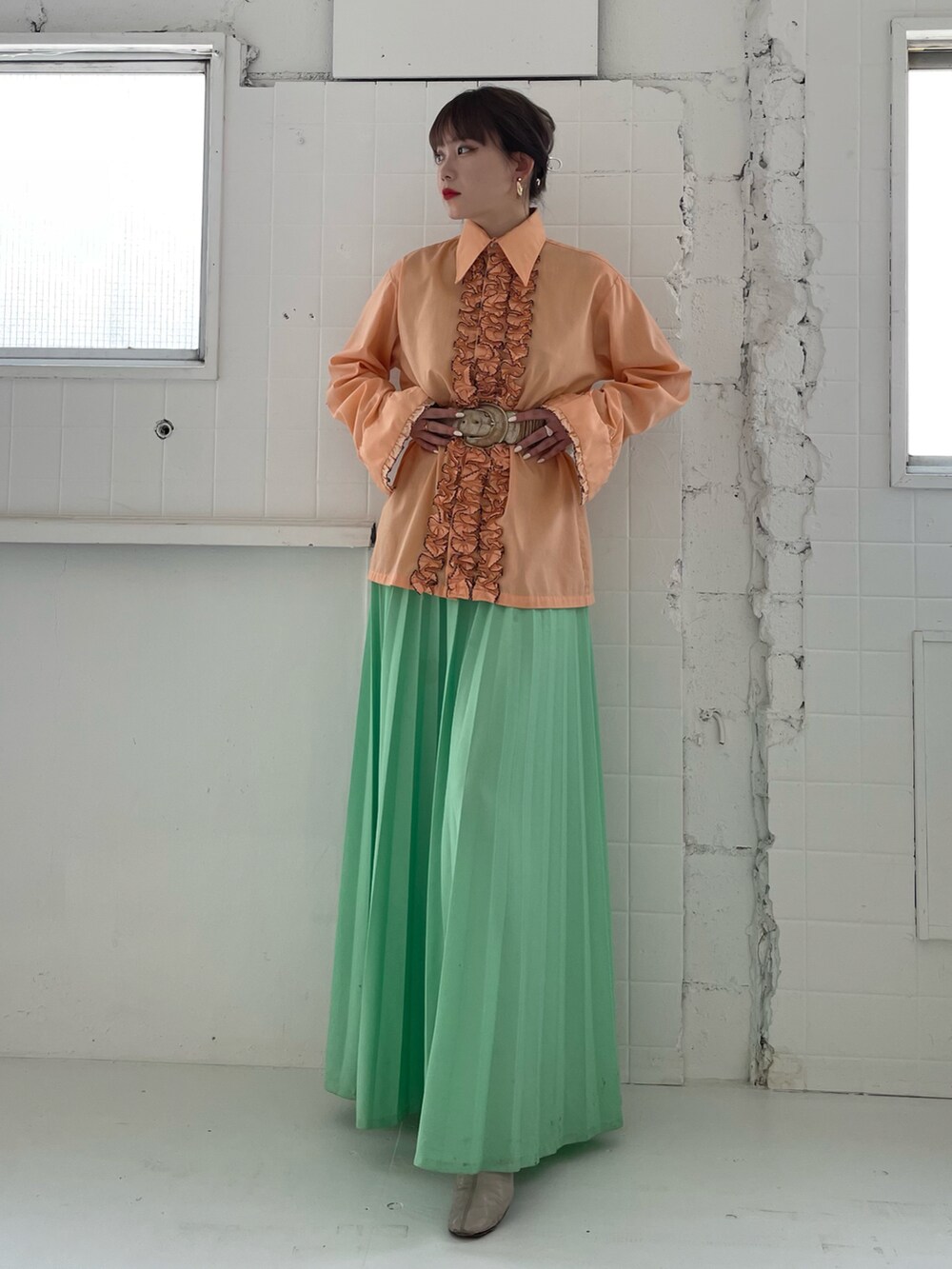 オレンジ系のトップスを着用したレディースの夏コーディネートの3枚目の写真