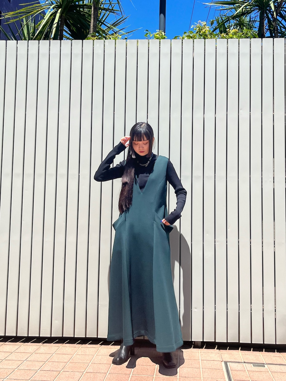 グリーン系のワンピース、ブラック系のパンプス、ブラック系のニット/セーターを着用したレディースの冬コーディネートの2枚目の写真