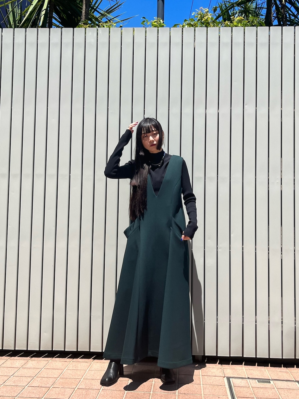 グリーン系のワンピース、ブラック系のパンプス、ブラック系のニット/セーターを着用したレディースの冬コーディネートの9枚目の写真