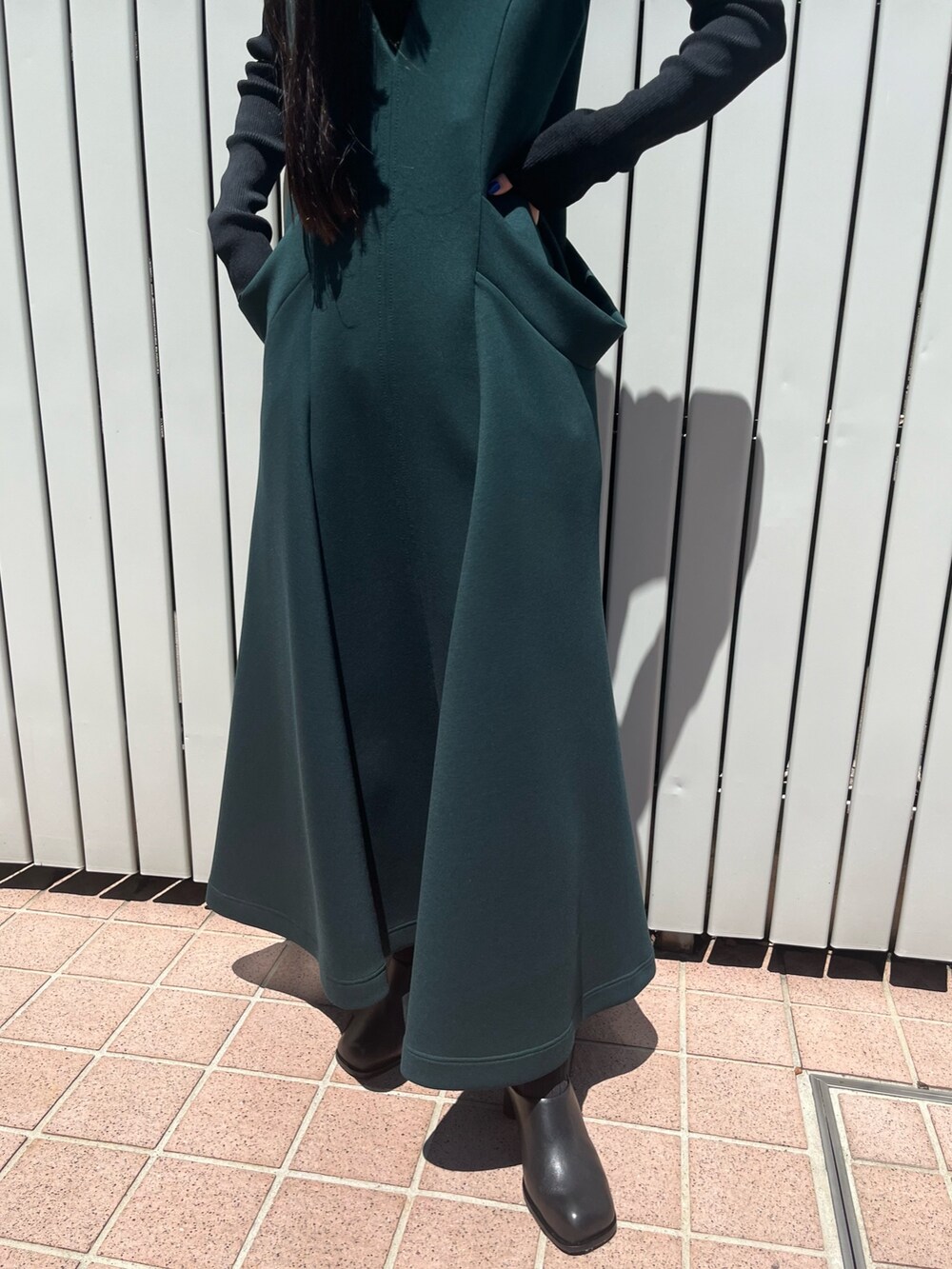 グリーン系のワンピース、ブラック系のパンプス、ブラック系のニット/セーターを着用したレディースの冬コーディネートの8枚目の写真