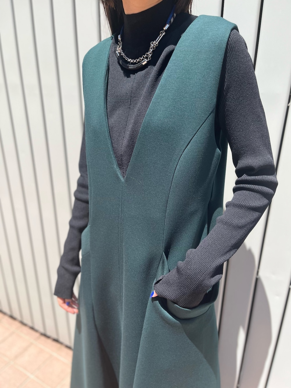 グリーン系のワンピース、ブラック系のパンプス、ブラック系のニット/セーターを着用したレディースの冬コーディネートの6枚目の写真