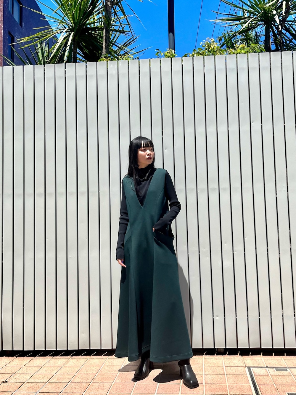 グリーン系のワンピース、ブラック系のパンプス、ブラック系のニット/セーターを着用したレディースの冬コーディネートの10枚目の写真