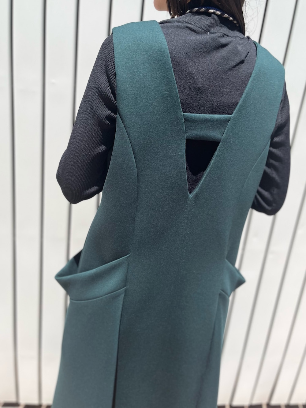 グリーン系のワンピース、ブラック系のパンプス、ブラック系のニット/セーターを着用したレディースの冬コーディネートの7枚目の写真