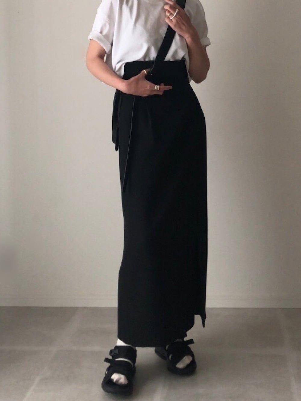 ブラック系のスカート、ホワイト系のTシャツ/カットソー、その他のサンダルを着用したレディースの春コーディネートの3枚目の写真