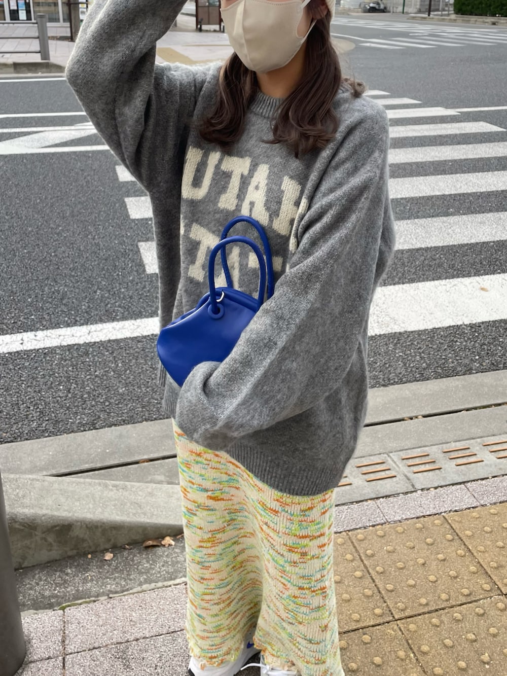 グレー系のニット/セーター、ブルー系のショルダーバッグ、グリーン系のスカートを着用したレディースの秋コーディネートの4枚目の写真