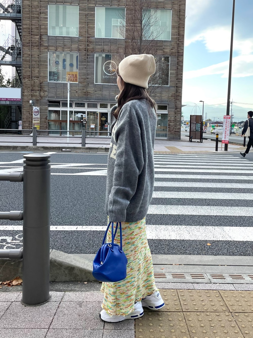 グレー系のニット/セーター、ブルー系のショルダーバッグ、グリーン系のスカートを着用したレディースの秋コーディネートの2枚目の写真