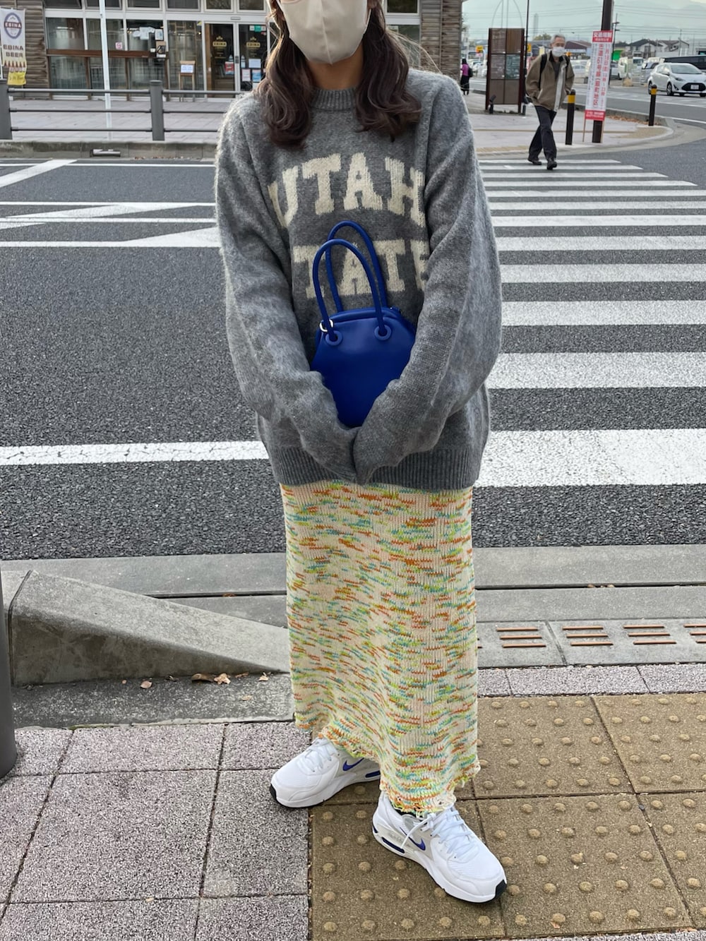 グレー系のニット/セーター、ブルー系のショルダーバッグ、グリーン系のスカートを着用したレディースの秋コーディネートの3枚目の写真