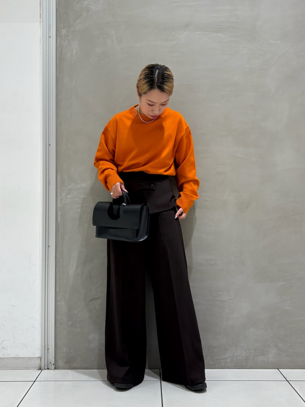 オレンジ系のニット/セーター、ブラウン系のその他パンツ、ブラック系のブーツを着用したレディースの秋コーディネートの3枚目の写真