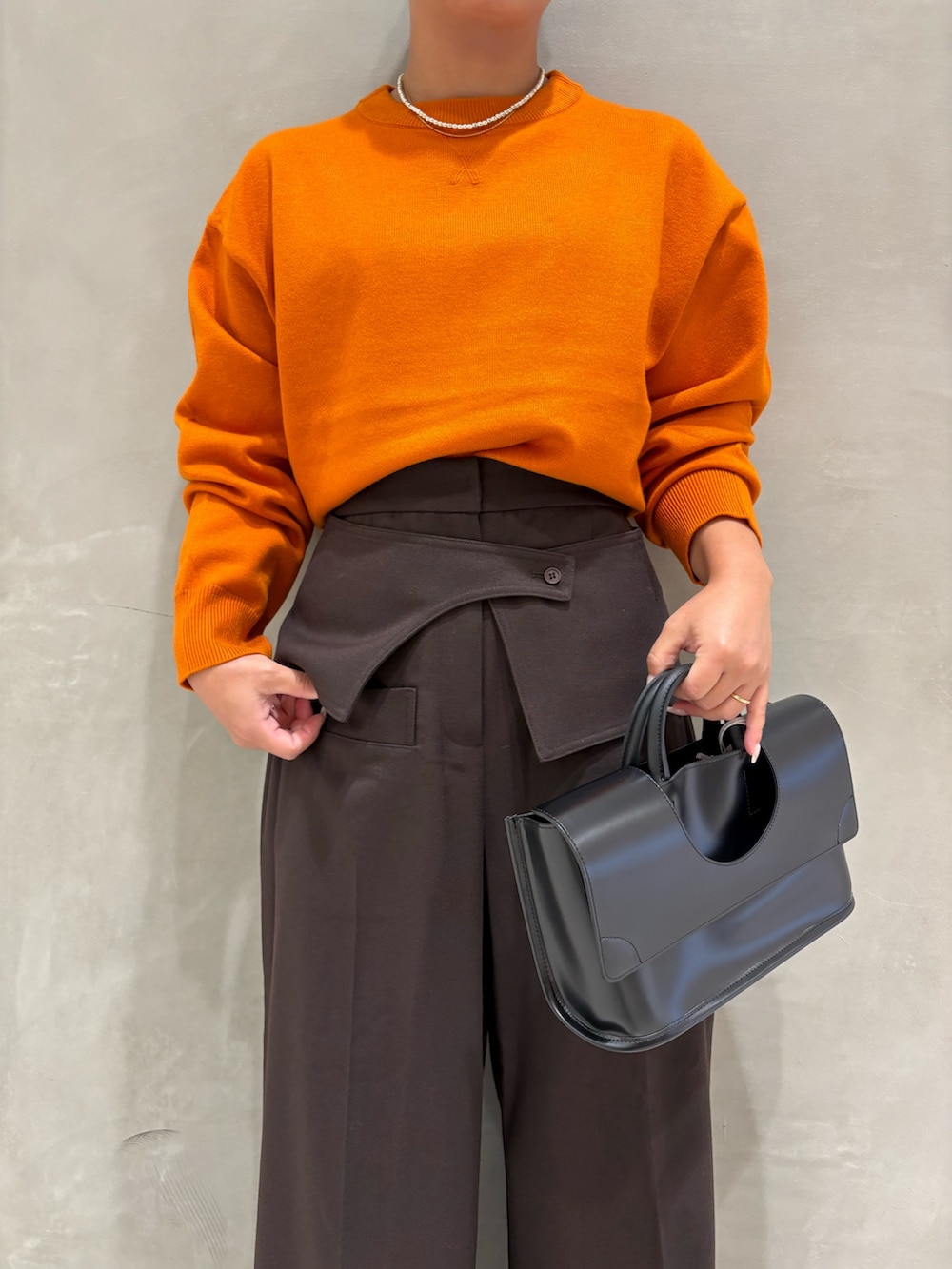オレンジ系のニット/セーター、ブラウン系のその他パンツ、ブラック系のブーツを着用したレディースの秋コーディネートの4枚目の写真