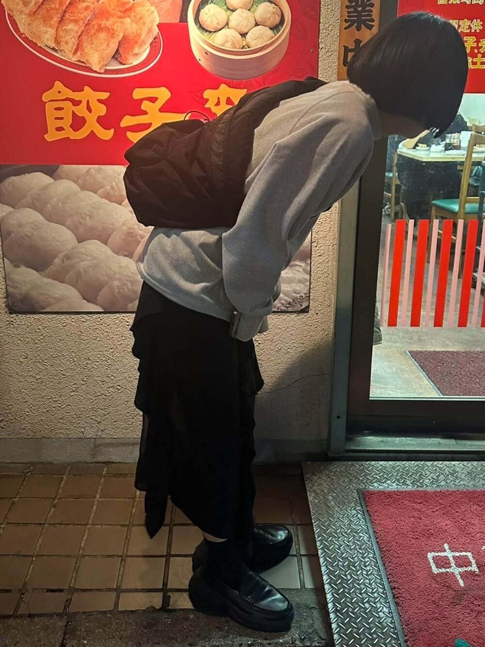 グレー系のスウェット、ブラック系のローファー、ブラック系のスカートを着用したレディースの春コーディネートの2枚目の写真