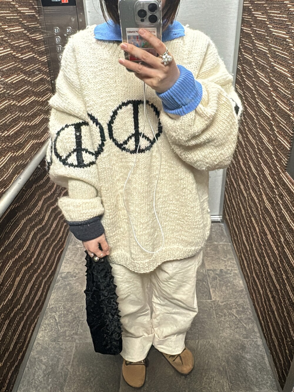 ホワイト系のニット/セーター、ブラック系のハンドバッグ、ブラウン系のスニーカーを着用したレディースの冬コーディネートの2枚目の写真