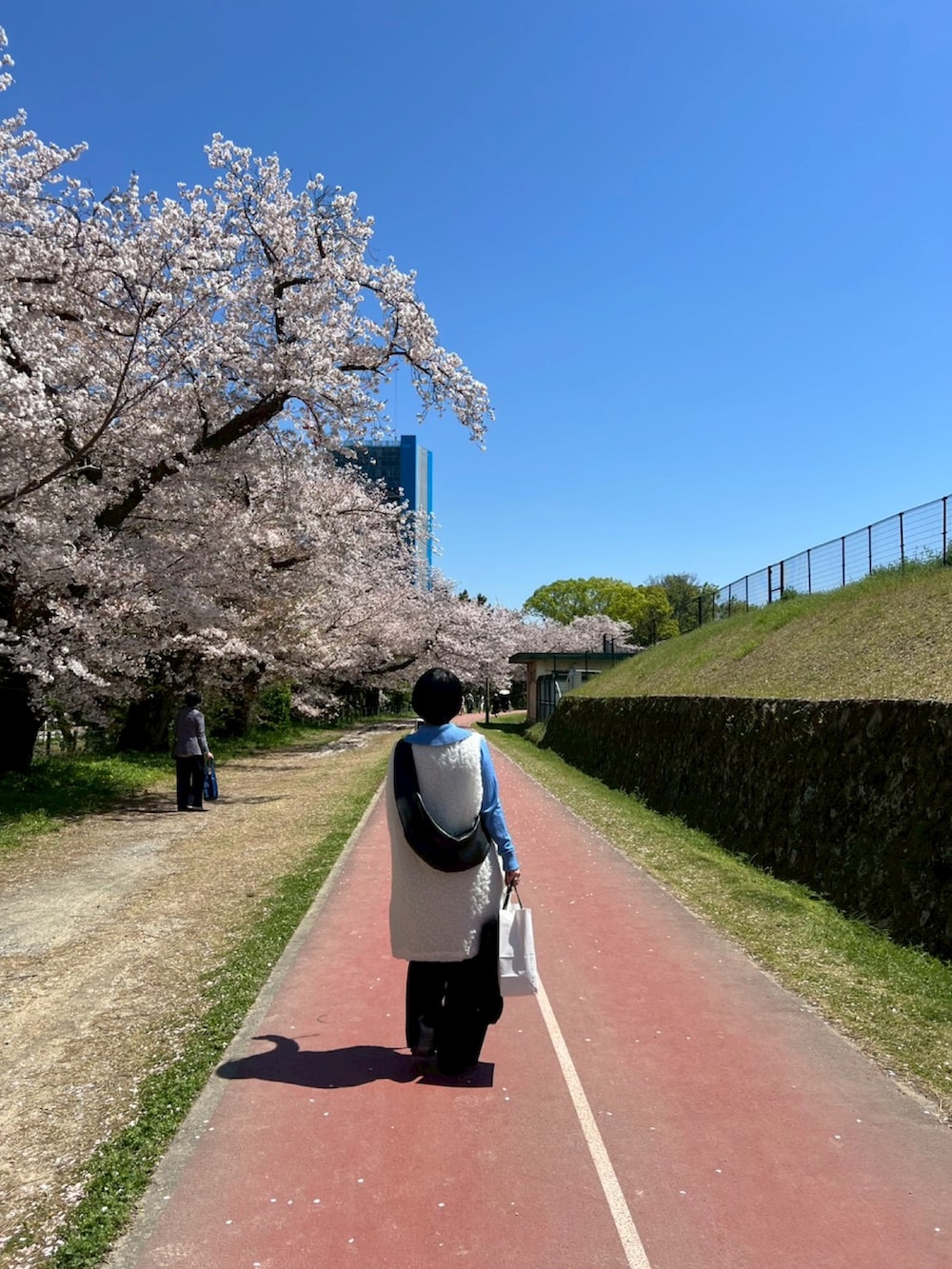 ブルー系のニット/セーター、ホワイト系のその他トップス、ブラック系のパンプスを着用したレディースの春コーディネートの3枚目の写真