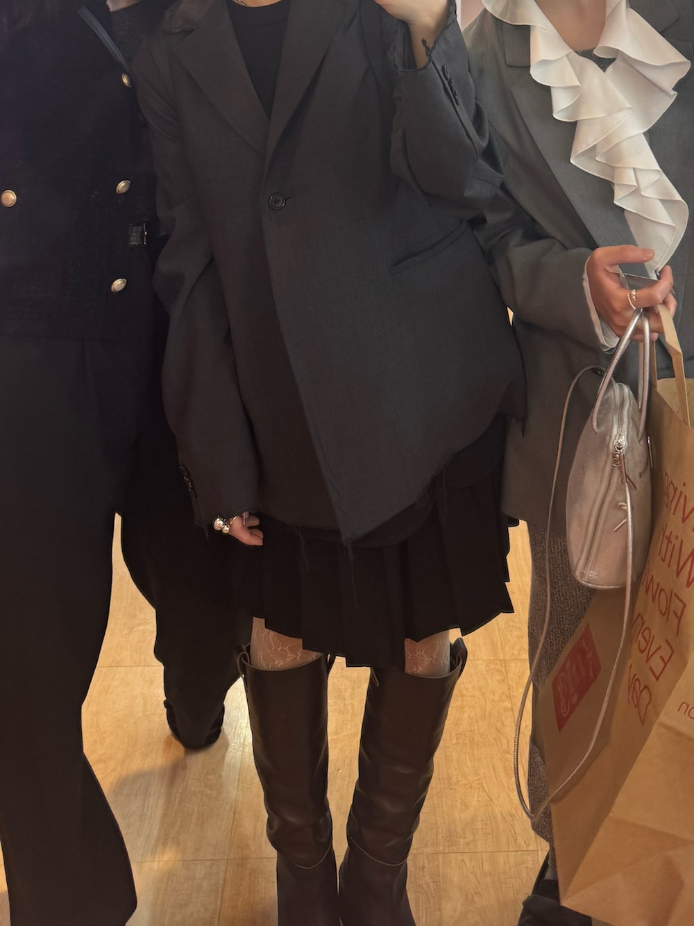 ブラック系のスカート、グレー系のテーラードジャケット、グレー系のバッグを着用したレディースの春コーディネートの2枚目の写真