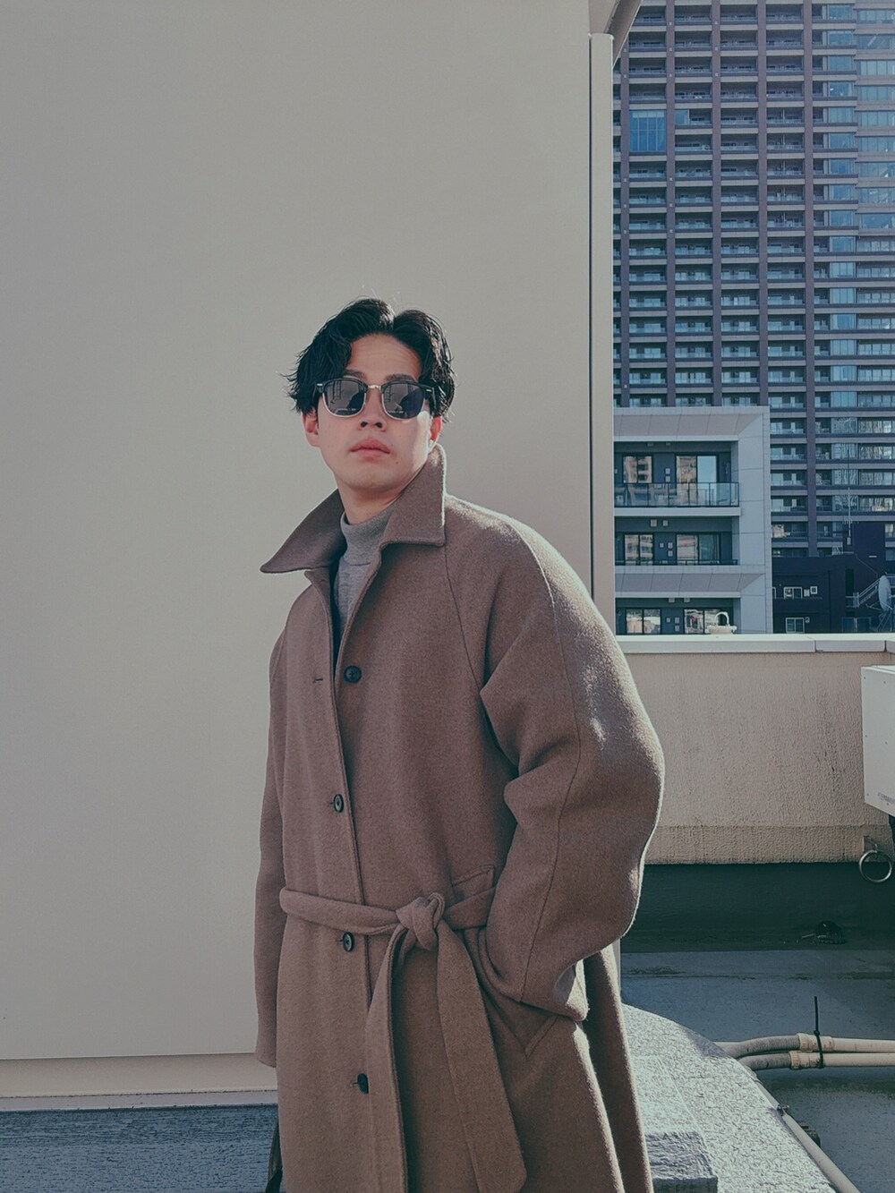 ブラウン系のトートバッグ、ベージュ系のステンカラーコート、ブラック系のドレスシューズを着用したメンズの冬コーディネートの3枚目の写真