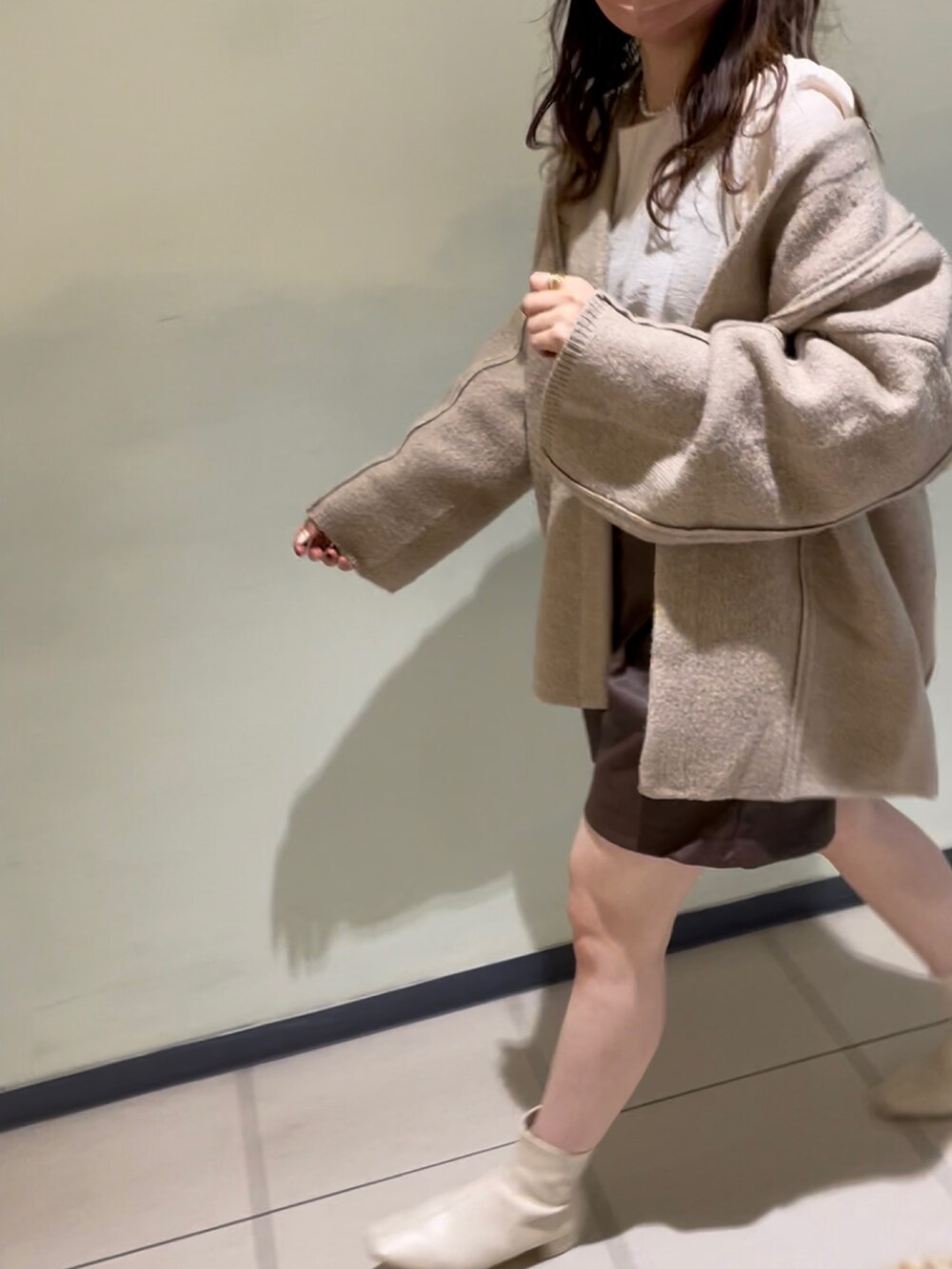 ベージュ系のノーカラーコート、ブラウン系のその他パンツ、ホワイト系のブーツを着用したレディースの秋コーディネートの3枚目の写真