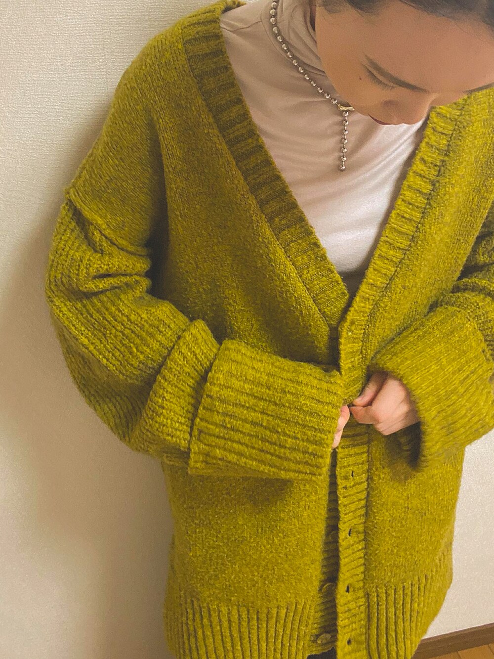 グリーン系のカーディガン/ボレロ、ベージュ系のTシャツ/カットソー、ホワイト系のスカートを着用したレディースの冬コーディネートの2枚目の写真