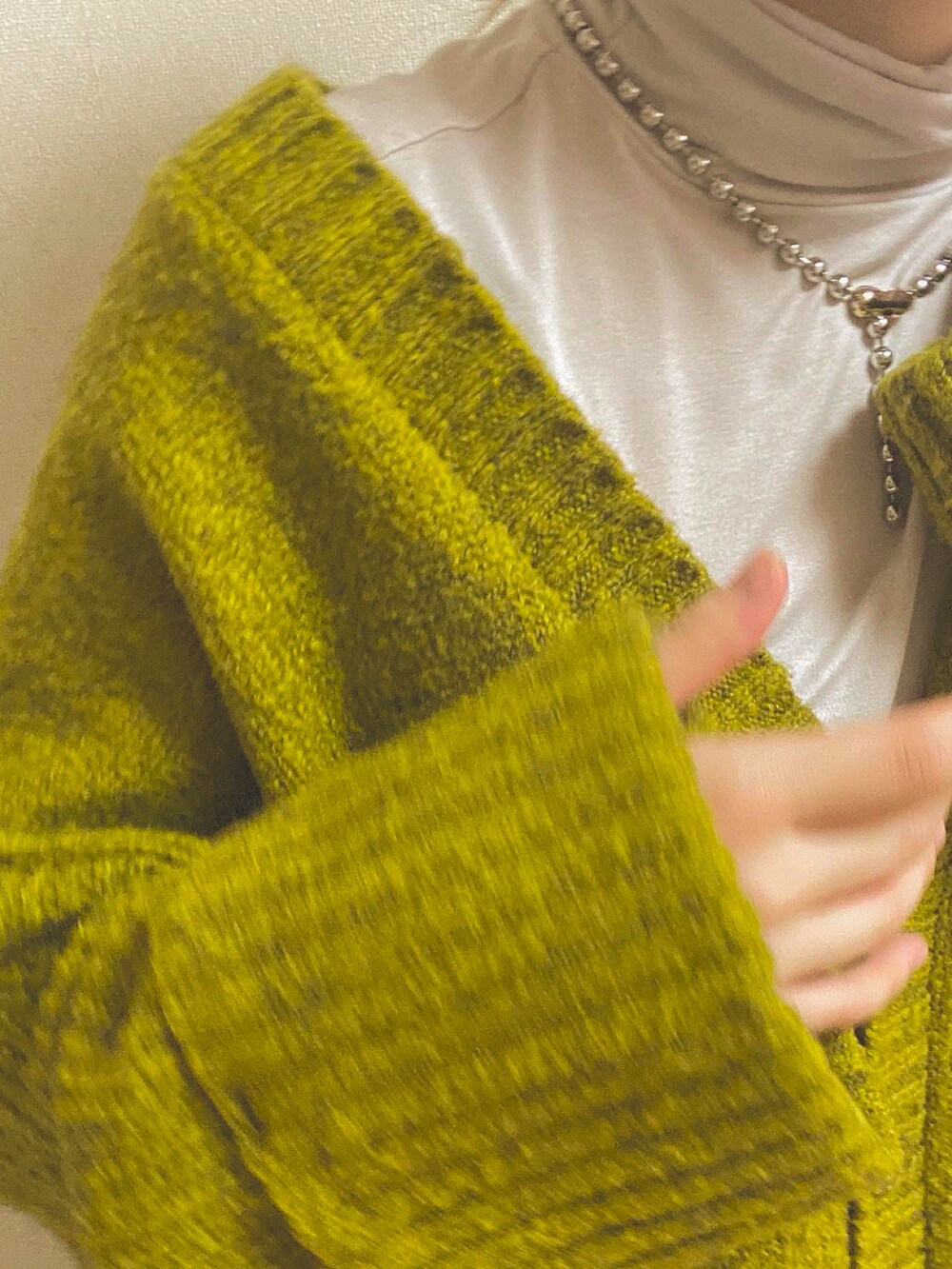 グリーン系のカーディガン/ボレロ、ベージュ系のTシャツ/カットソー、ホワイト系のスカートを着用したレディースの冬コーディネートの4枚目の写真