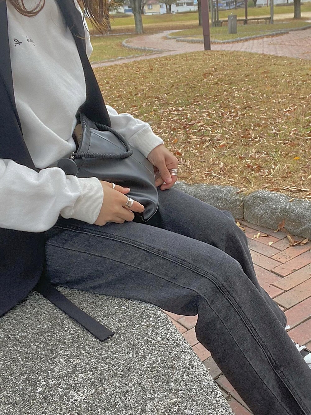 ブラック系のベスト、ホワイト系のスウェット、ブラック系のデニムパンツを着用したレディースの冬コーディネートの2枚目の写真