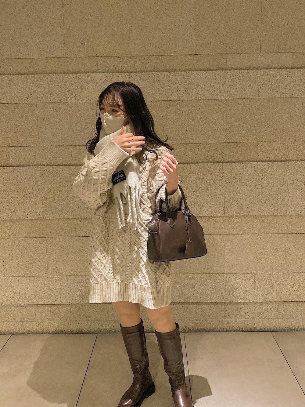 ブラウン系のブーツ、ブラウン系のボストンバッグ、ホワイト系のニット/セーターを着用したレディースの冬コーディネートの2枚目の写真