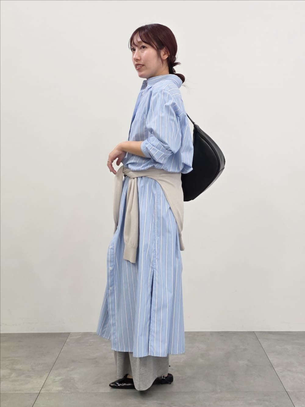 ブルー系のシャツワンピース、グレー系のスウェットパンツ、ベージュ系のニット/セーターを着用したレディースの春コーディネートの3枚目の写真