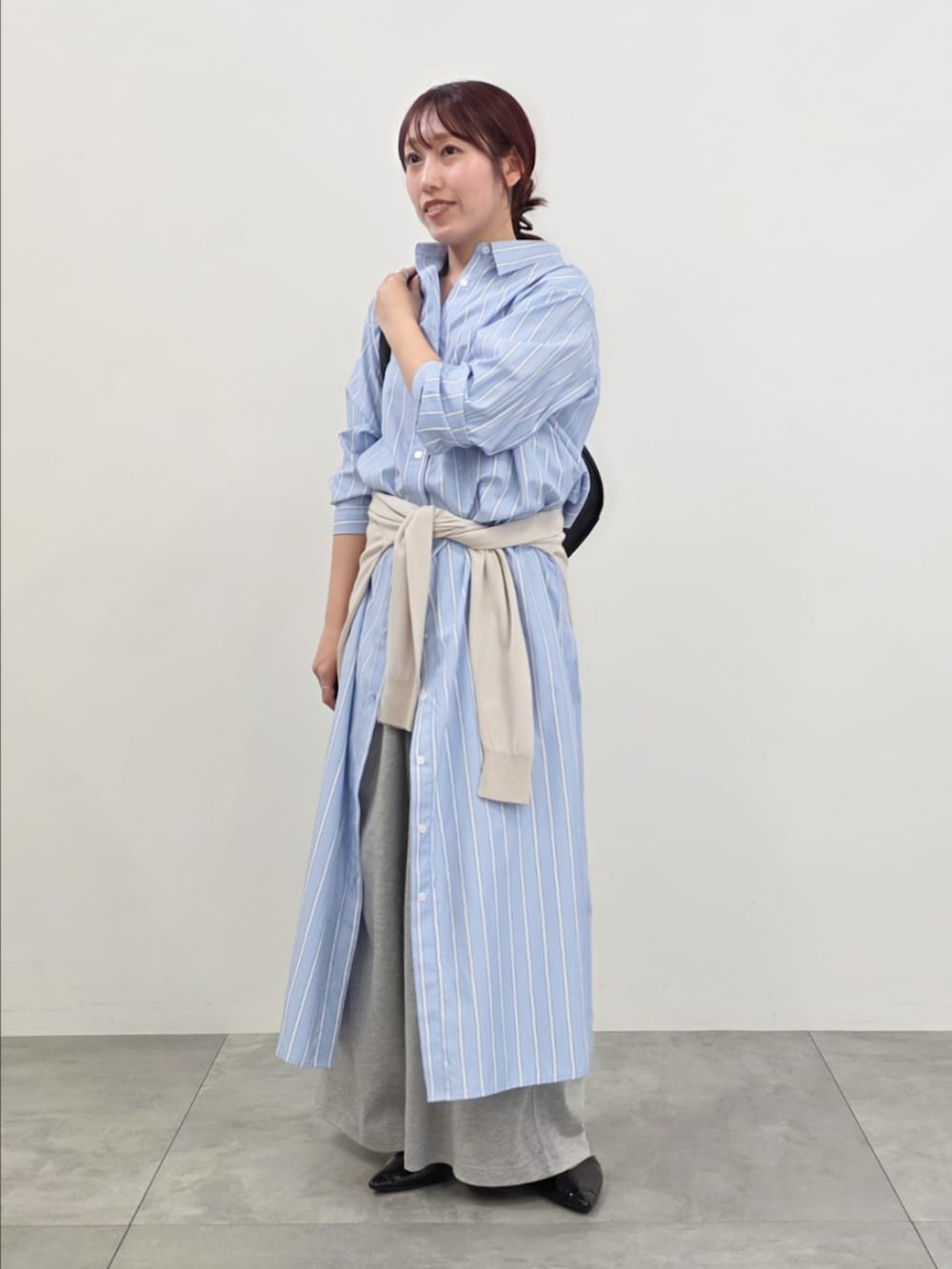 ブルー系のシャツワンピース、グレー系のスウェットパンツ、ベージュ系のニット/セーターを着用したレディースの春コーディネートの2枚目の写真