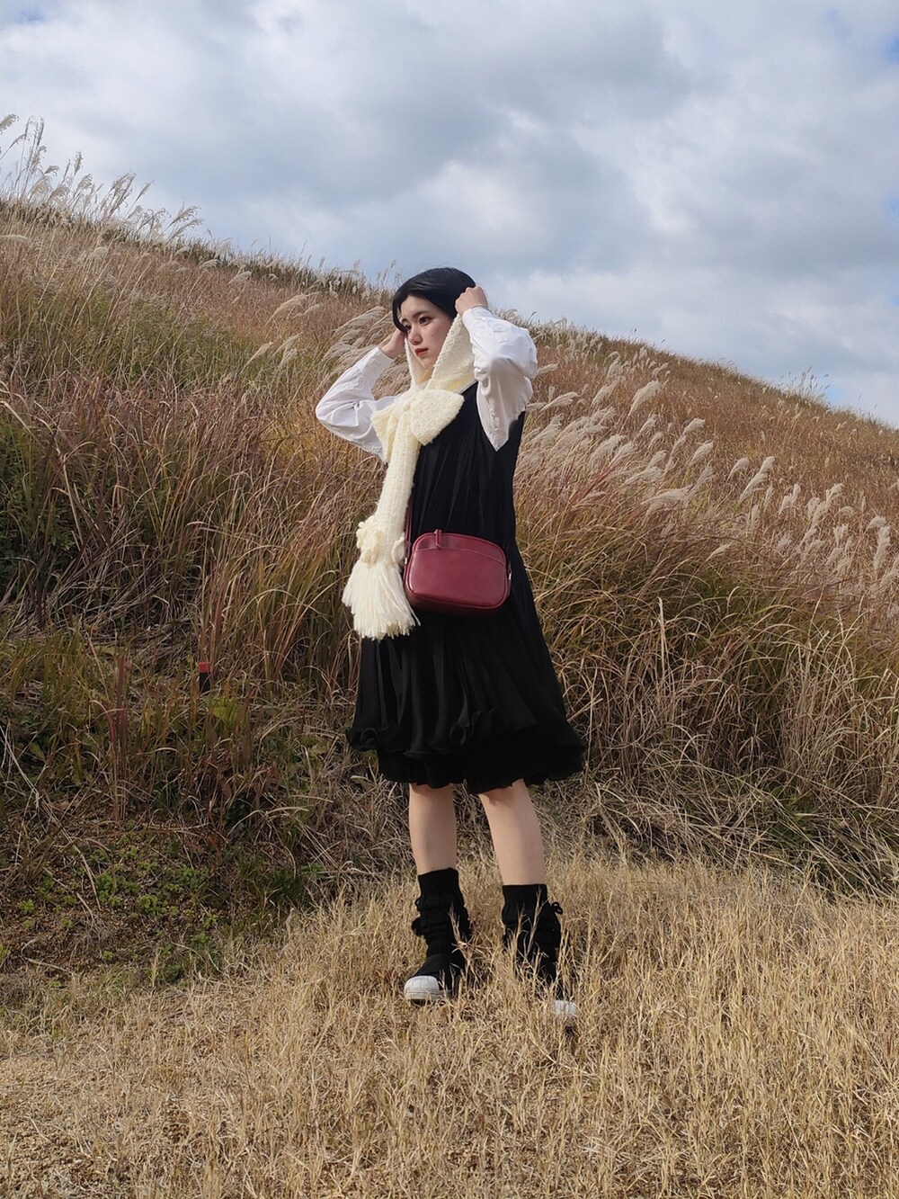 ブラック系のスカート、ホワイト系のマフラーを着用したレディースの冬コーディネートの2枚目の写真