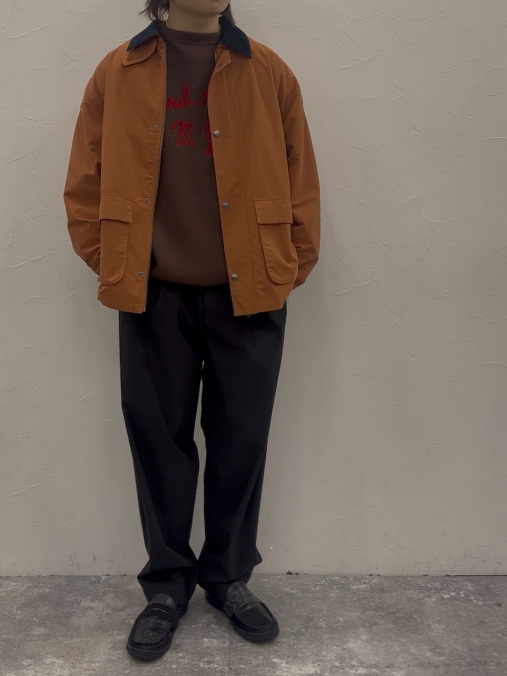 オレンジ系のブルゾン、ブラウン系のニット/セーター、ブラック系のスラックスを着用したメンズの秋コーディネートの2枚目の写真