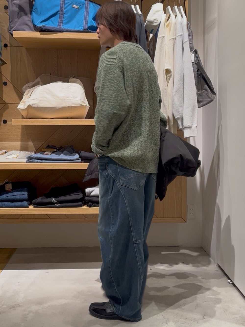 グリーン系のニット/セーター、ブラック系のブルゾン、ブルー系のデニムパンツを着用したメンズの冬コーディネートの3枚目の写真