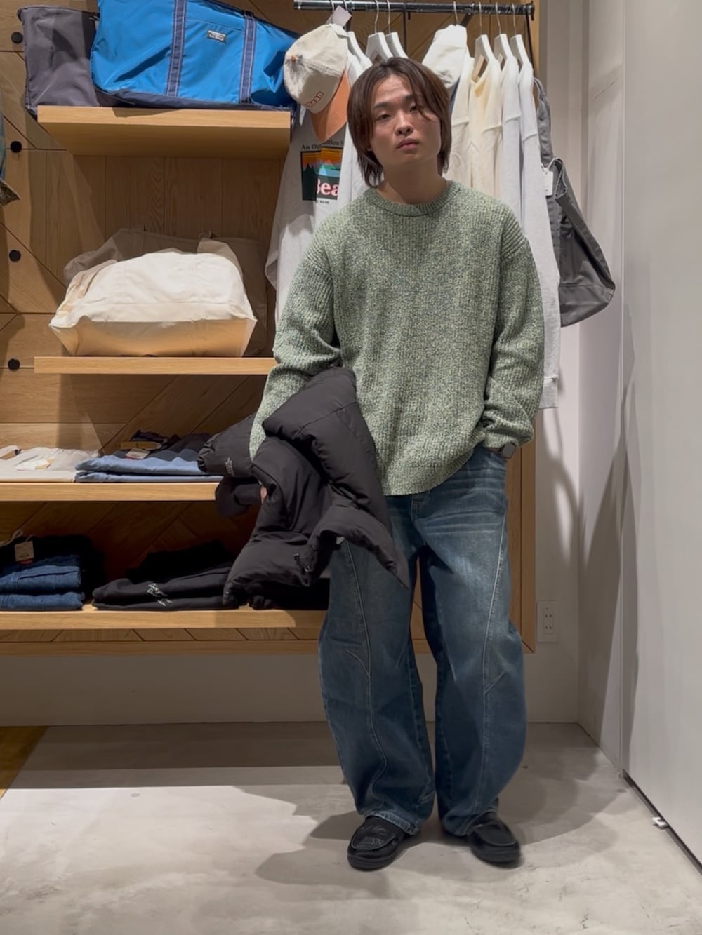 グリーン系のニット/セーター、ブラック系のブルゾン、ブルー系のデニムパンツを着用したメンズの冬コーディネートの5枚目の写真