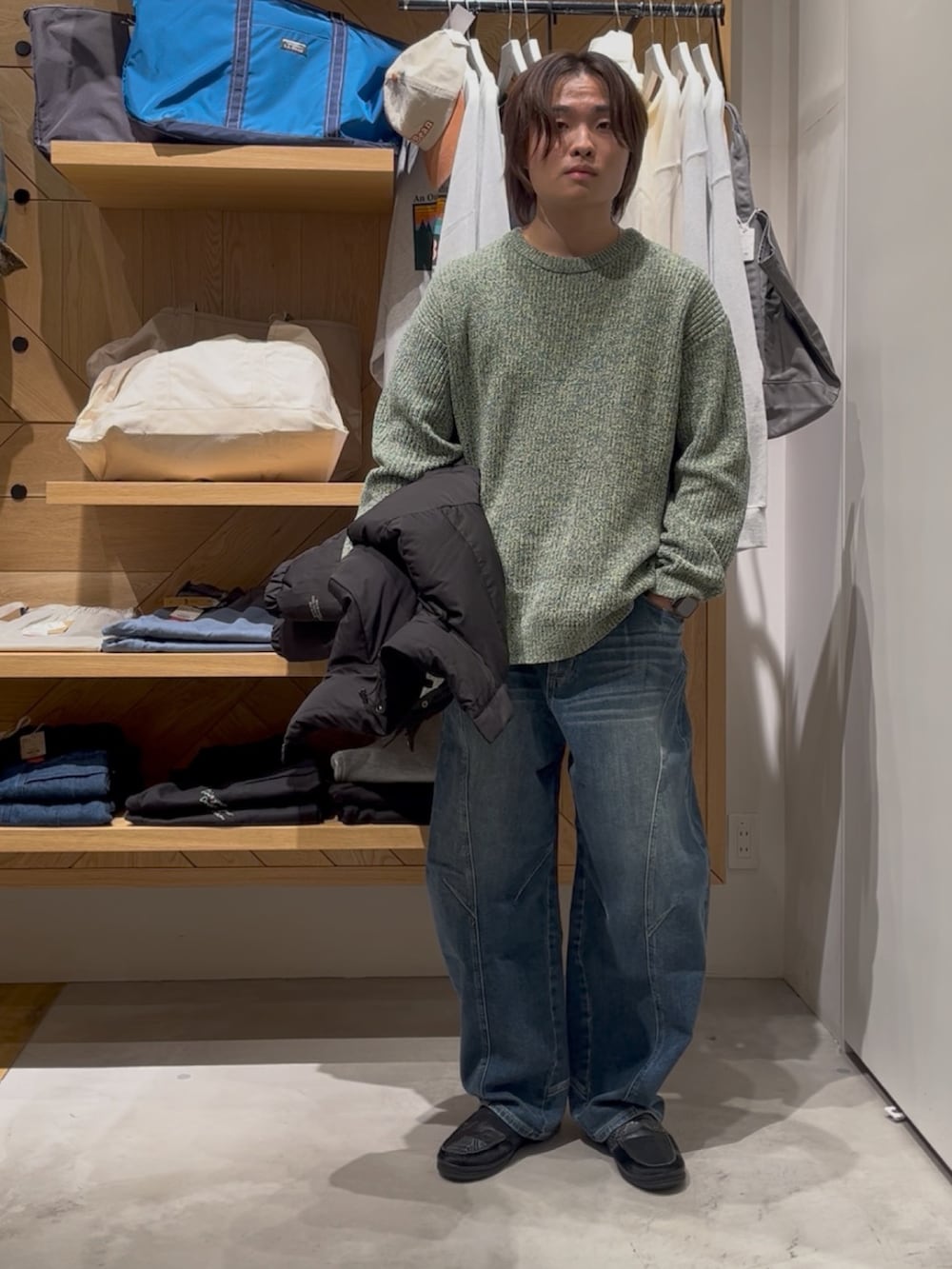 グリーン系のニット/セーター、ブラック系のブルゾン、ブルー系のデニムパンツを着用したメンズの冬コーディネートの2枚目の写真