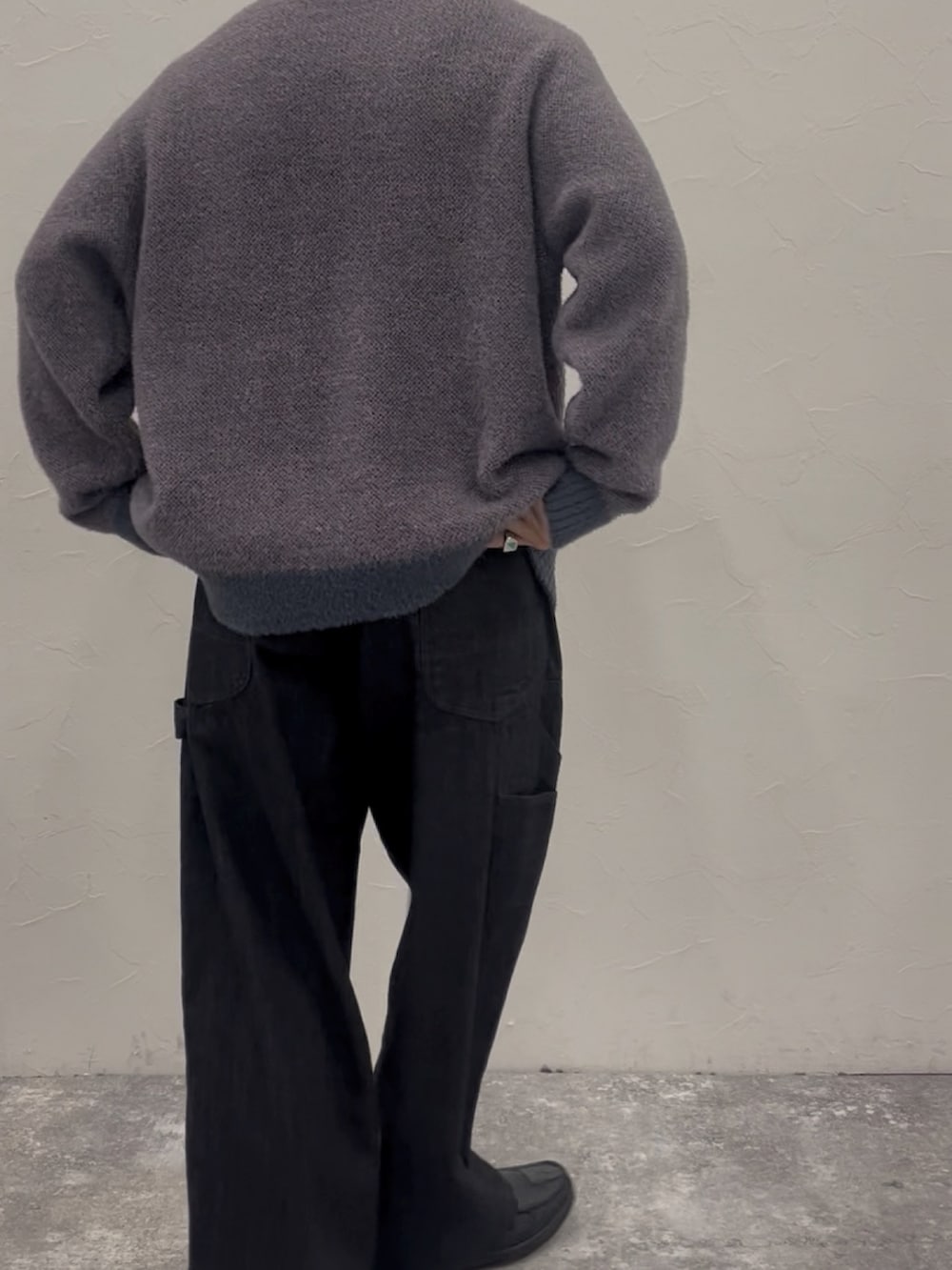 パープル系のニット/セーター、ブラック系のデニムパンツ、ブラック系のローファーを着用したメンズの秋コーディネートの3枚目の写真