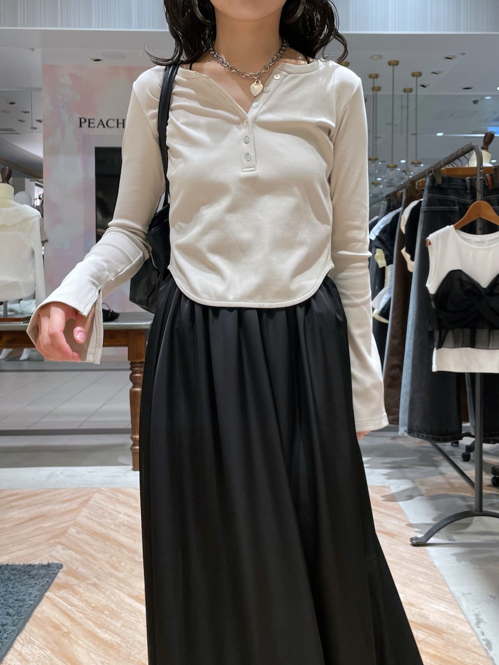 ブラック系のトートバッグ、ホワイト系のTシャツ/カットソー、ブラック系のスカートを着用したレディースの秋コーディネートの2枚目の写真
