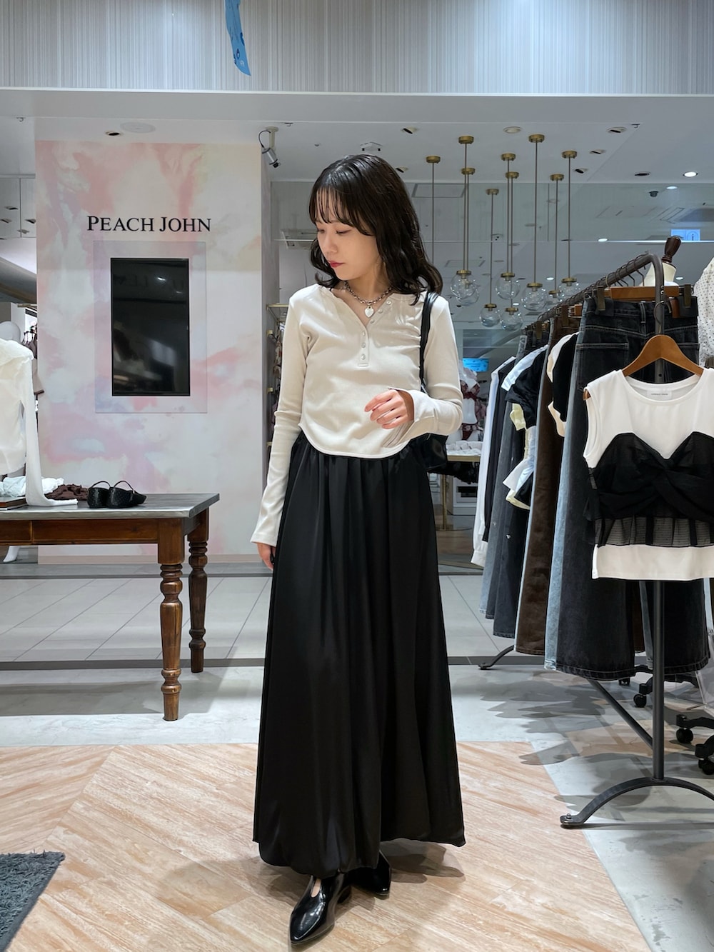 ブラック系のトートバッグ、ホワイト系のTシャツ/カットソー、ブラック系のスカートを着用したレディースの秋コーディネートの6枚目の写真