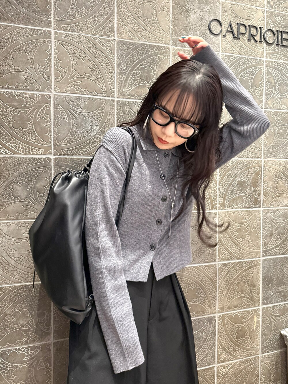 ブラック系のバックパック/リュック、ブラック系のその他パンツ、グレー系のカーディガン/ボレロを着用したレディースの冬コーディネートの2枚目の写真