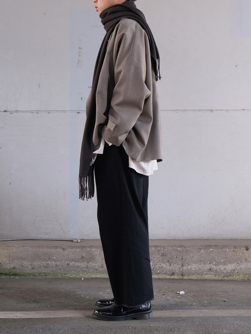 グレー系のトレンチコート、ホワイト系のシャツ/ブラウス、ブラック系のデニムパンツを着用したメンズの秋コーディネートの3枚目の写真