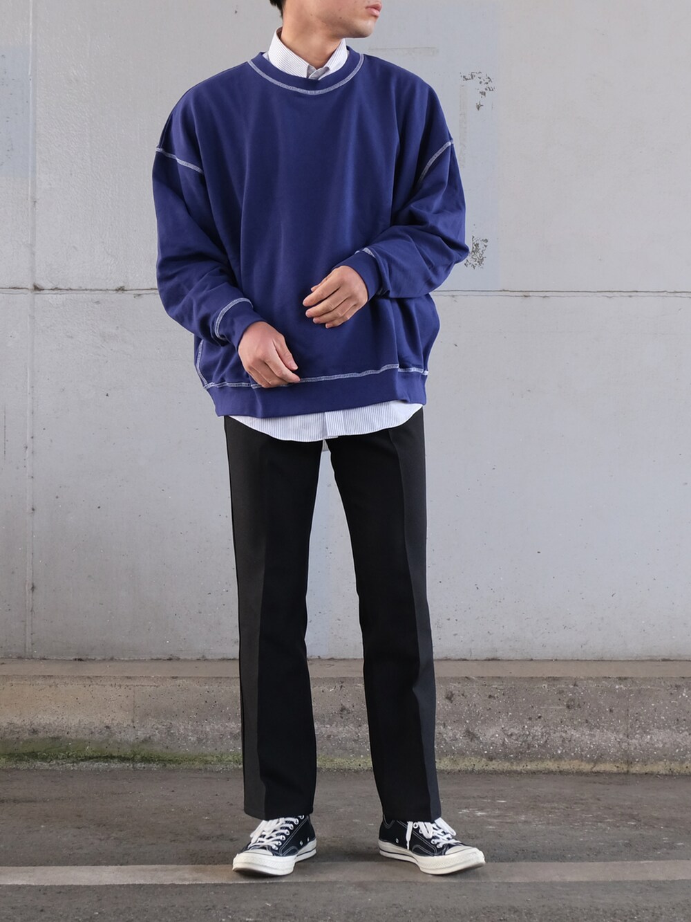 ブルー系のスウェット、ブラック系のデニムパンツ、ブラック系のスニーカーを着用したメンズの冬コーディネートの2枚目の写真