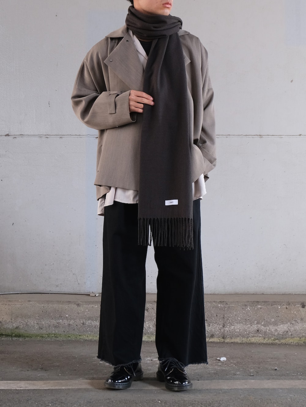 グレー系のトレンチコート、ホワイト系のシャツ/ブラウス、ブラック系のデニムパンツを着用したメンズの秋コーディネートの2枚目の写真