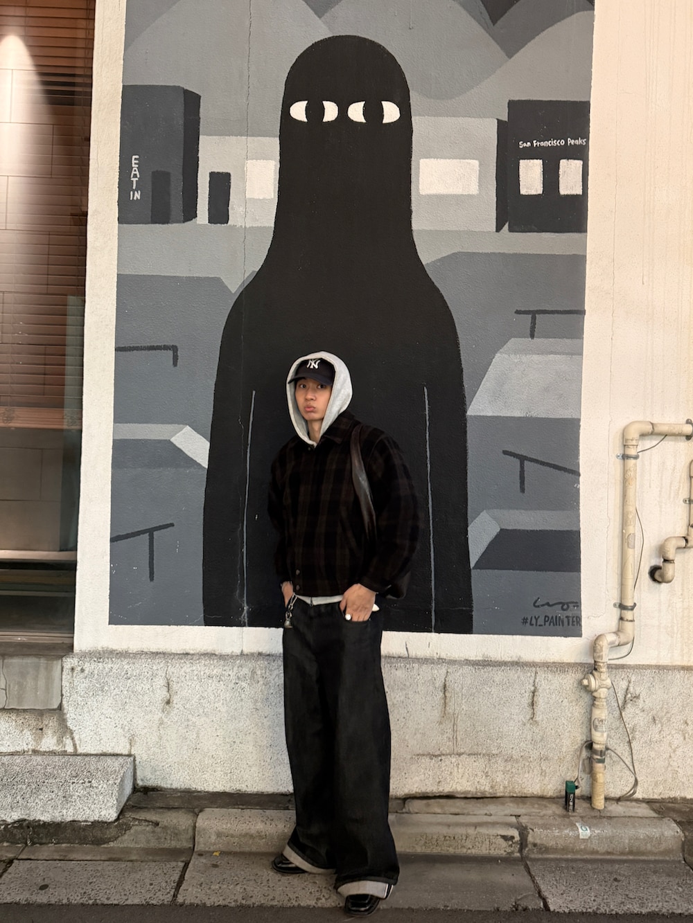 グレー系のパーカー、ブラック系のデニムパンツ、ブルー系のキャップを着用したメンズの冬コーディネートの2枚目の写真