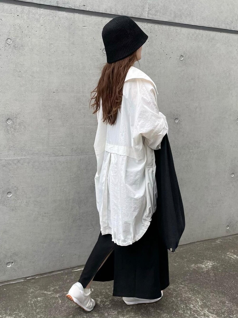 ホワイト系のブルゾン、ブラック系のワンピース、ブラック系のハンドバッグを着用したレディースの春コーディネートの2枚目の写真