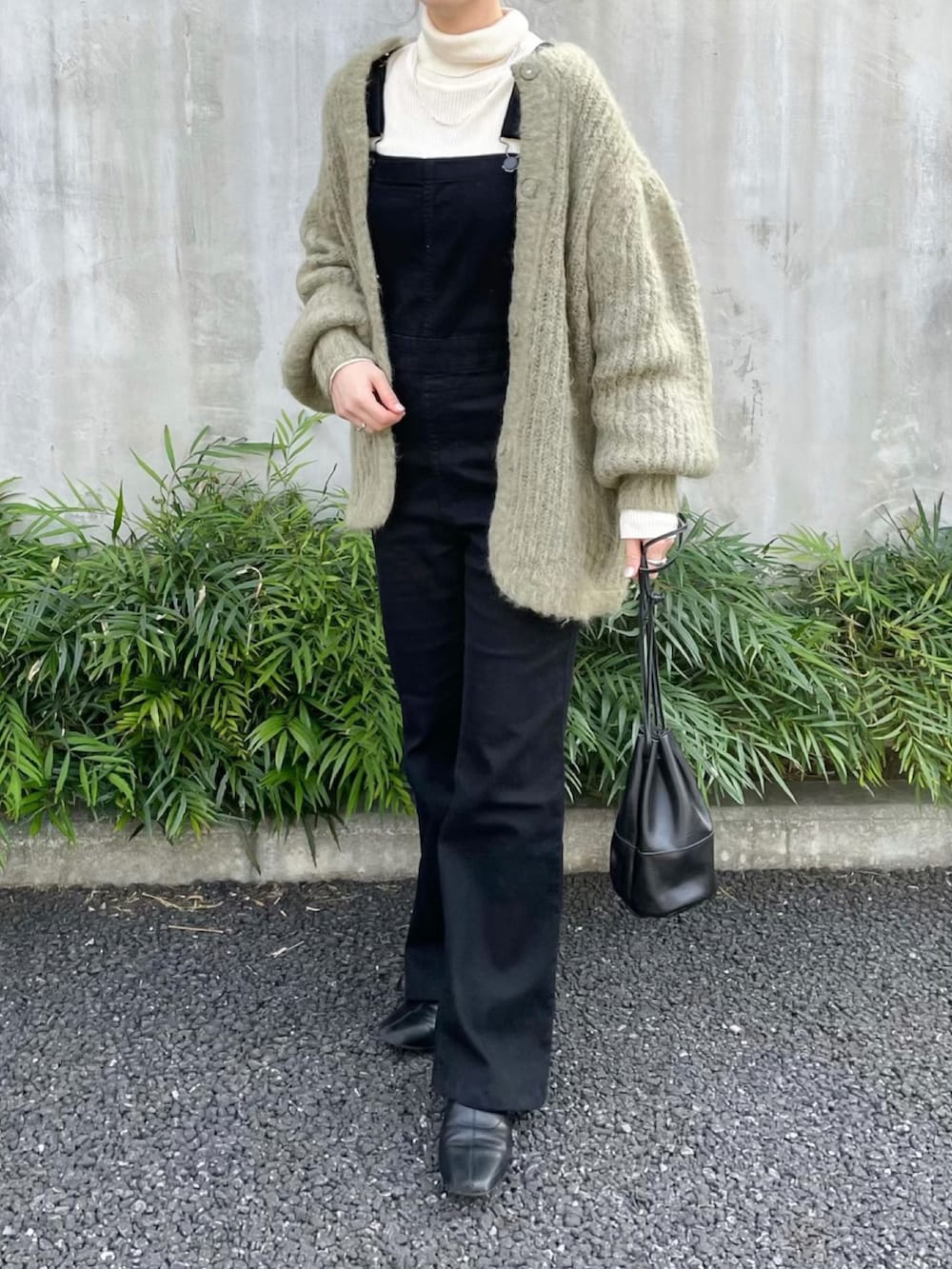ブラック系のサロペット/オーバーオール、ブラック系のハンドバッグ、ブラック系のブーツを着用したレディースの冬コーディネートの2枚目の写真